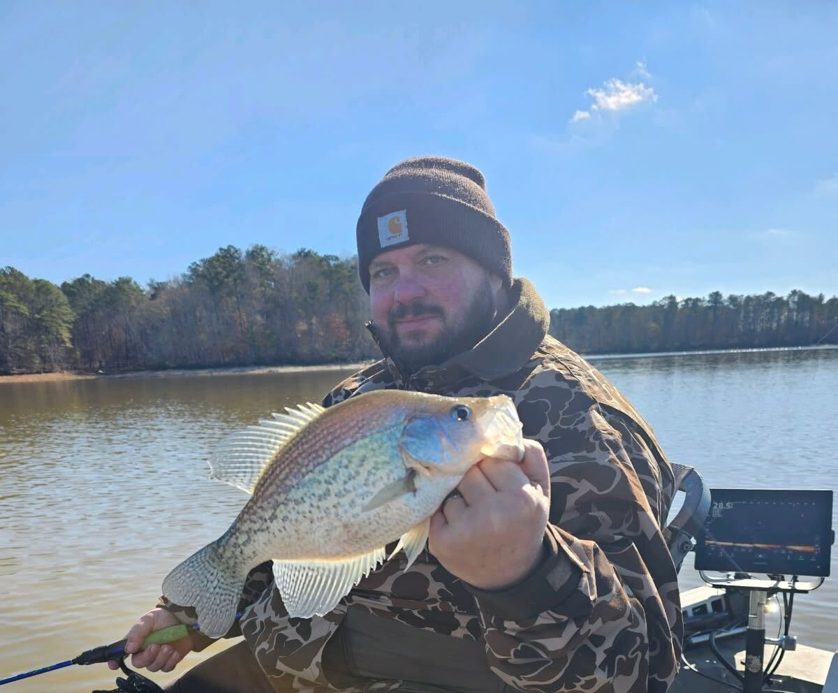 Fisherman in a boat holding a large crappie fish