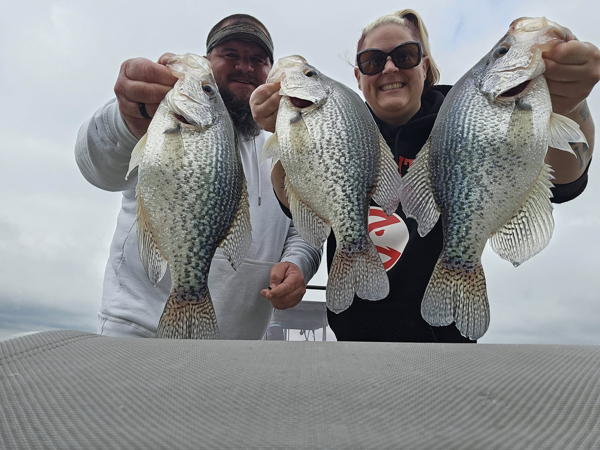 Man and woman holding up 3 crappie fish